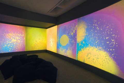 Installation. Clouds and splashes of lemon yellow, rose pink, grape purple, and aqua blue are projected onto gallery walls.