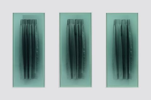 Multimedia. Three black and white photographs each show a curtain four pleats wide. Each is then covered with a sheet of seafoam-green glass and hung on a white gallery wall.