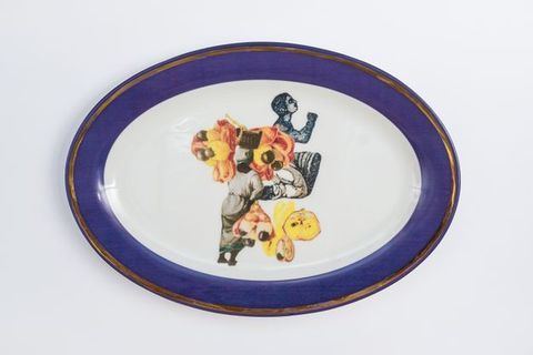 Porcelain. Dark-skinned people and other objects in yellow and peach appear collaged at the centre of this white oval plate. The cobalt-blue rim is edged in gold.